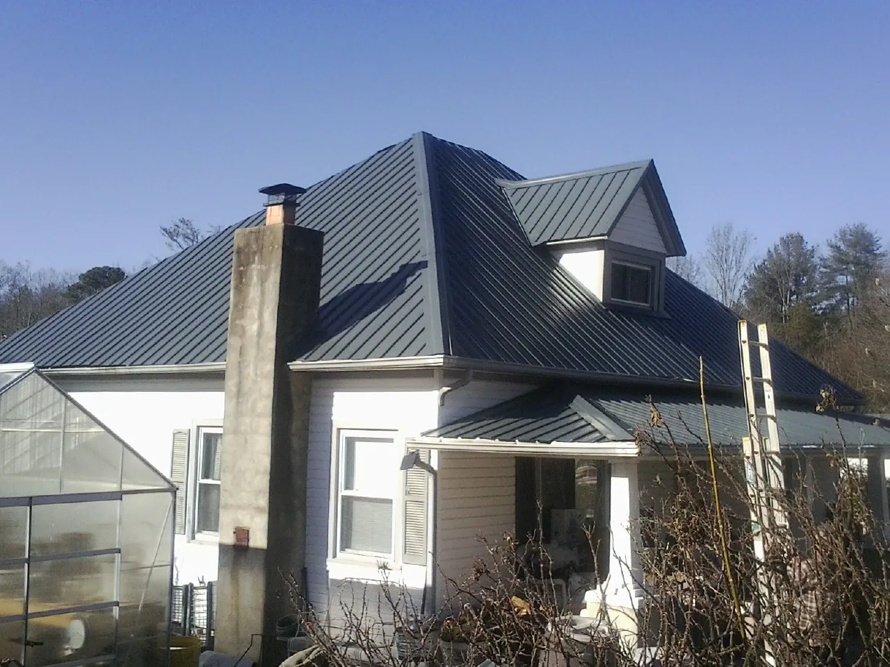 Dark blue standing seam metal roof on a white farmhouse with dormer — Slate & Tile Roof Repair by Roofing Brothers in Orland Park