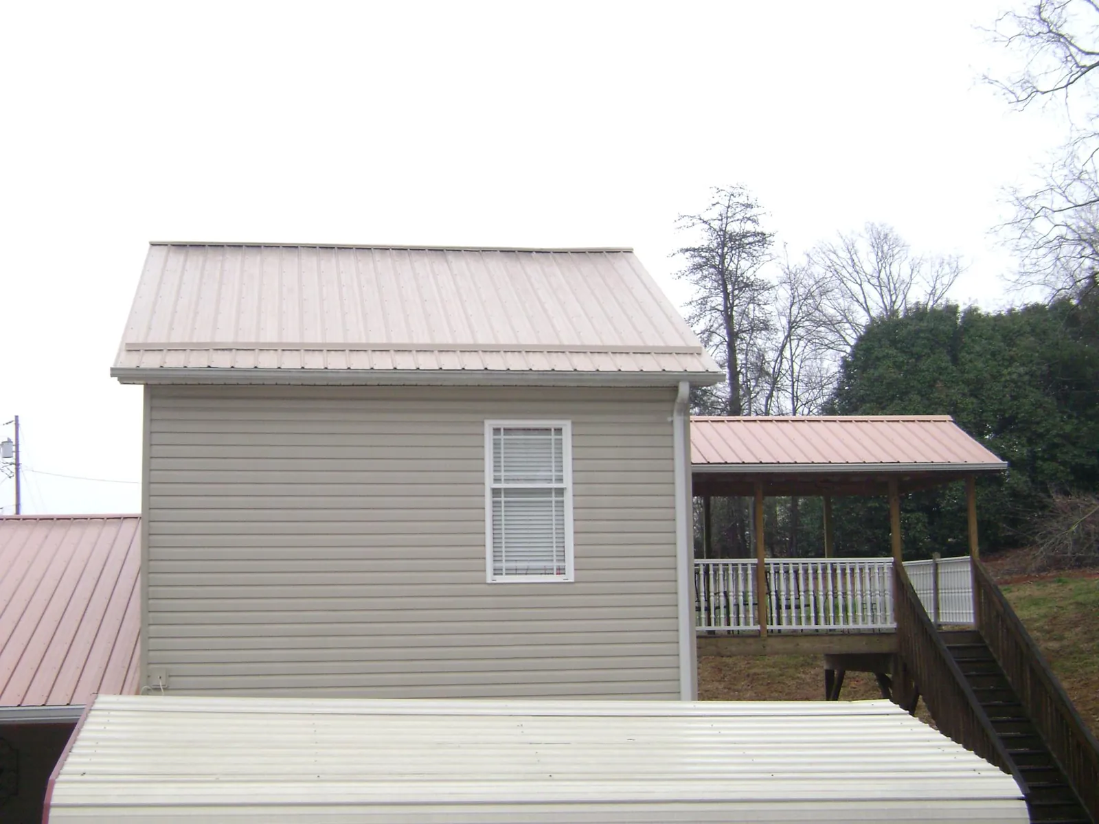 Tan metal roofs on a two story addition and attached porch, from a Roof Replacement job in Orland Park