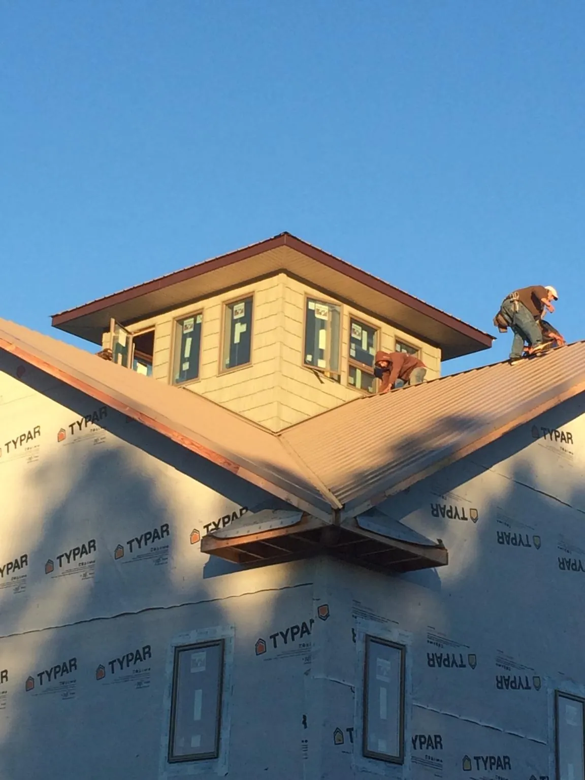 Roofers working around a rooftop cupola on a new metal roof at sunset — Roof Waterproofing in Orland Park by Roofing Brothers